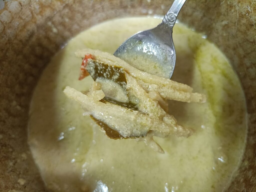 お皿に盛ったグリーンカレーをスプーンですくう実食写真