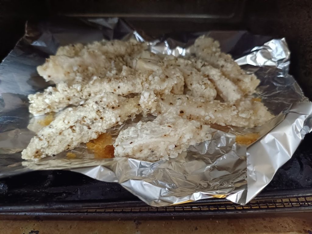 アルミホイルを敷いたトースターに入れたスパイシーチキンスティック