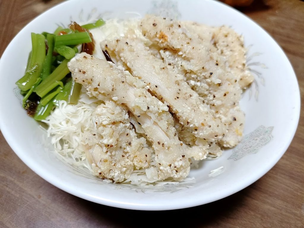 キャベツの千切りと野菜を添えたスパイシーチキンスティック