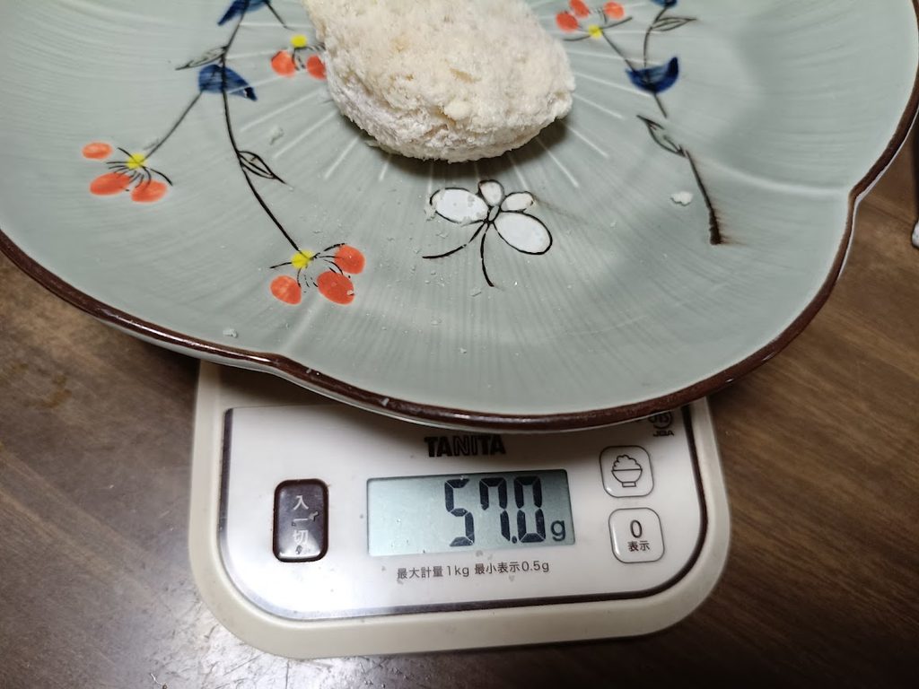 鶏屋さんのタルタルチキンカツ1個をキッチンスケールで計量した様子(57.0g・5個計測した中の最小値)