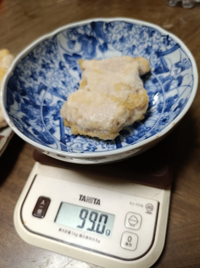 ジューシー油淋鶏セットのチキン1枚をキッチンスケールで計量した様子(99.0g・4枚中の最小値)