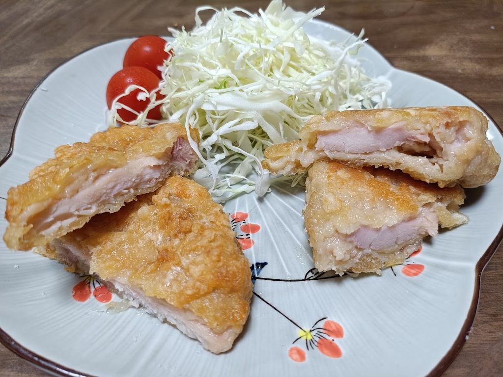皿に盛り付けたジューシー油淋鶏セットの断面(キャベツ・トマトを添えた)