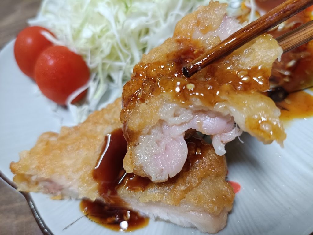 ソースをかけたジューシー油淋鶏セットを箸でつまんだ様子