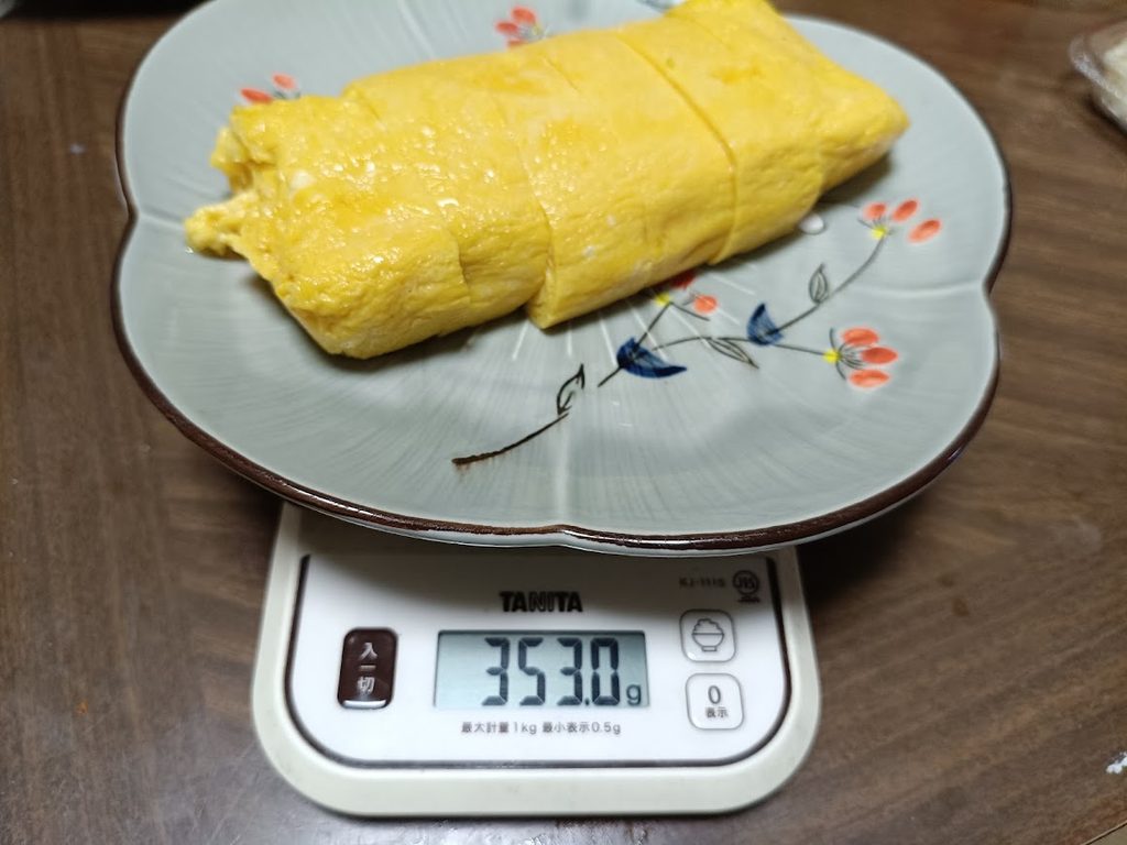 皿に乗せた鉄板巻上げ 自家製厚焼玉子をTANITAのスケールで計量(353.0g)