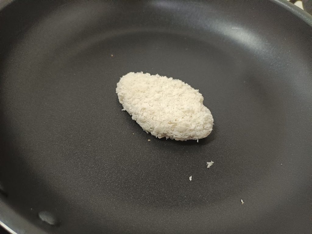 フライパンに入れた、冷凍のままのまぐろカツ1枚