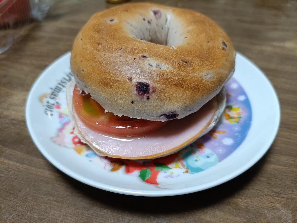 トマトとハムを挟んだクランベリーブルーベリーベーグルのアップ