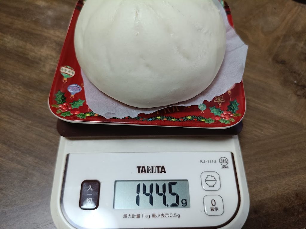 スケールで敷き紙込み144.5gと表示された金の豚まん