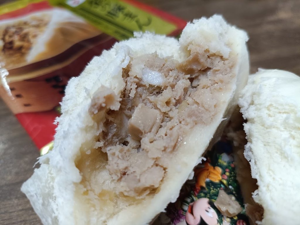 2つに割った金の豚まんの断面。豚肉とタケノコが入っている