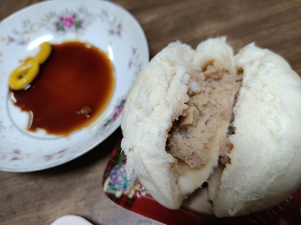 割った金の豚まんと、醤油とカラシを入れた小皿