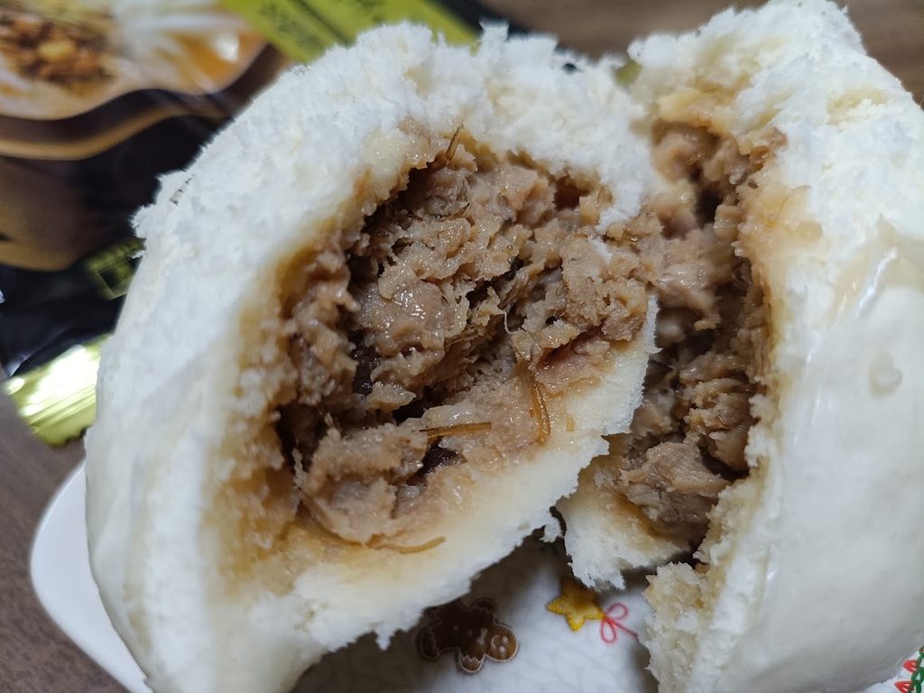 2つに割った金の肉まんの断面。肉がぎっしり入っている