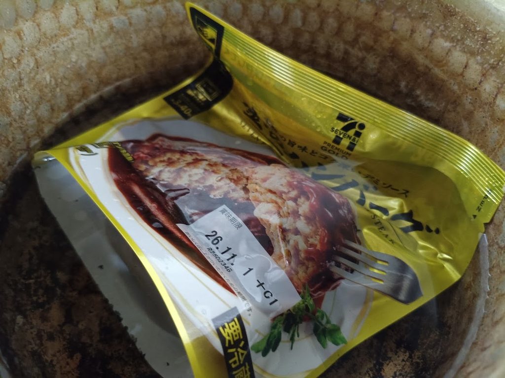 鍋の中で湯煎している袋入りの金のハンバーグ