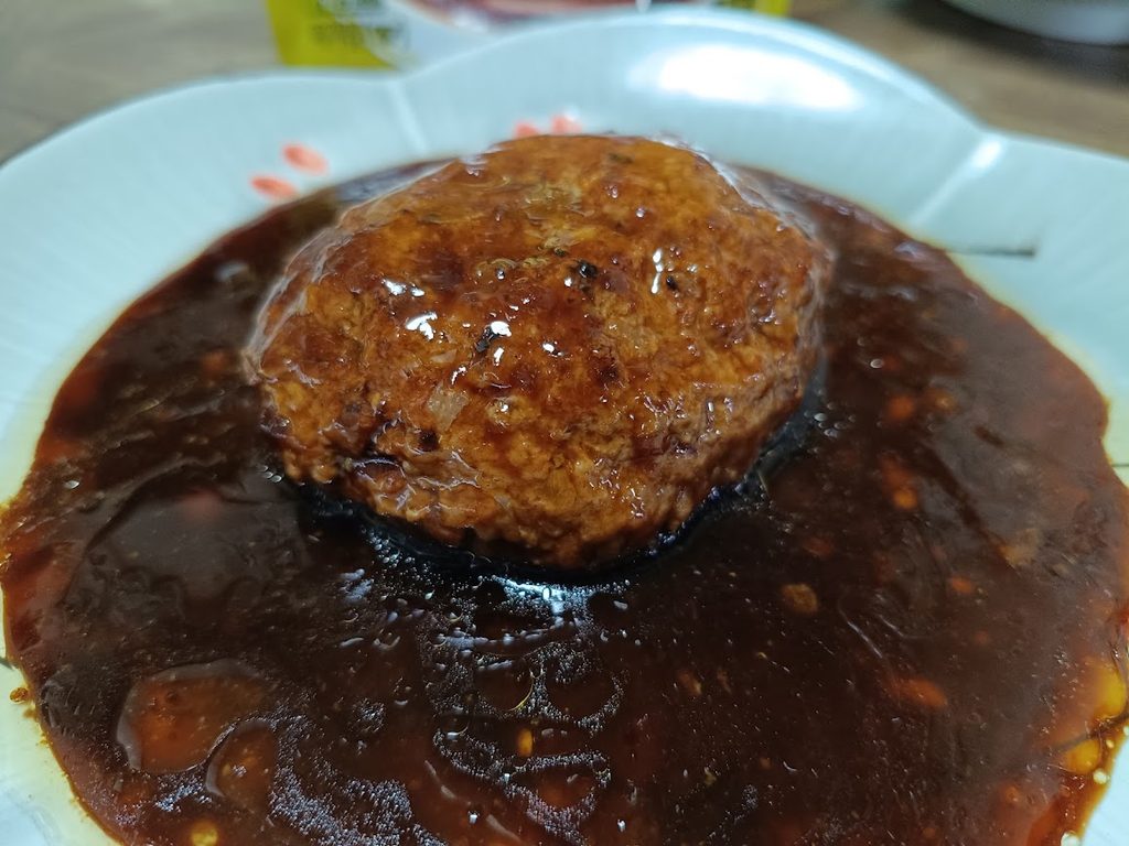 お皿に出したデミソースたっぷりの金のハンバーグ