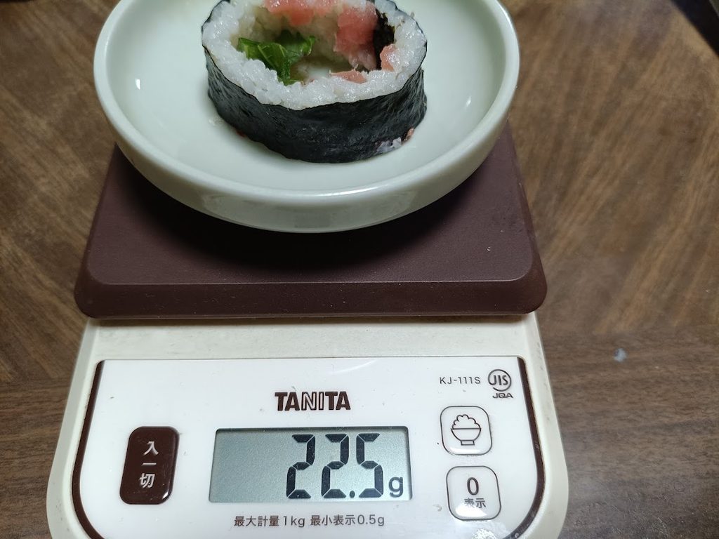 まぐろを抜いたごはん・海苔・しそだけの1個をお皿ごとはかりに載せた様子（22.5g）
