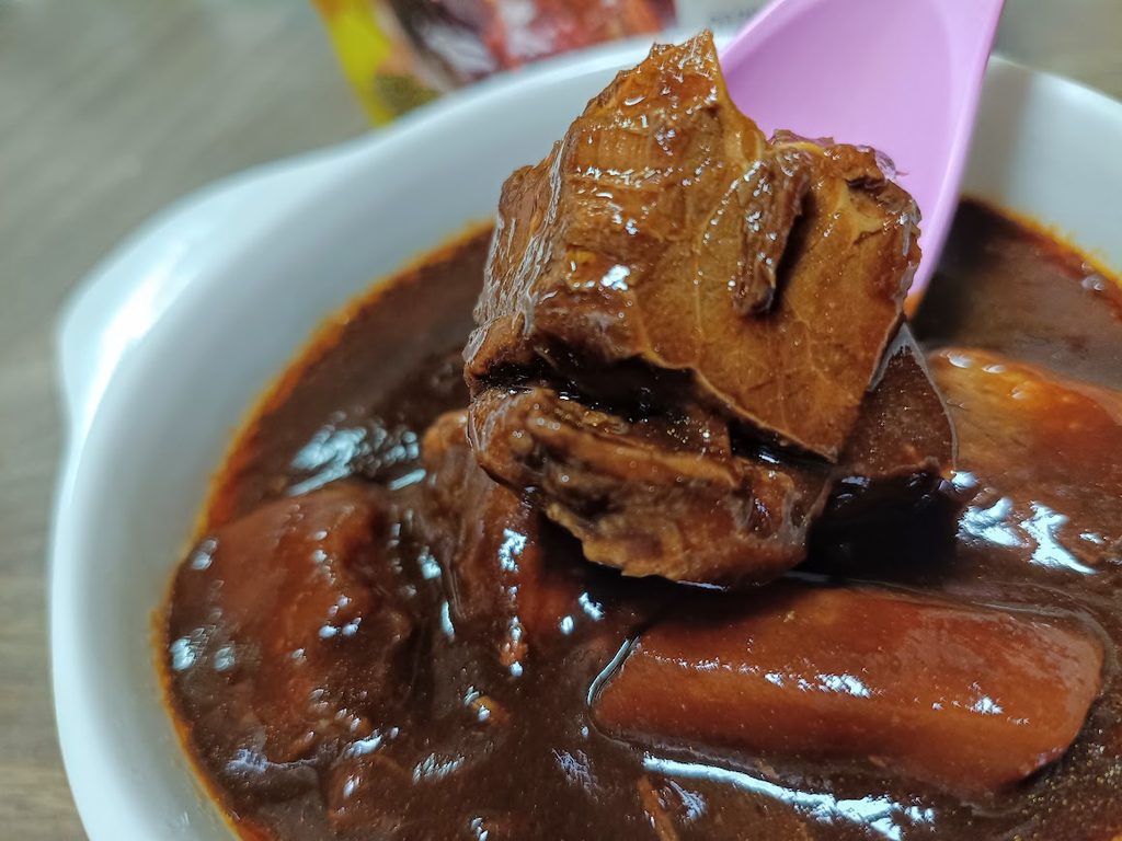 スプーンですくった牛肉の塊と、にんじんが見えるビーフシチュー