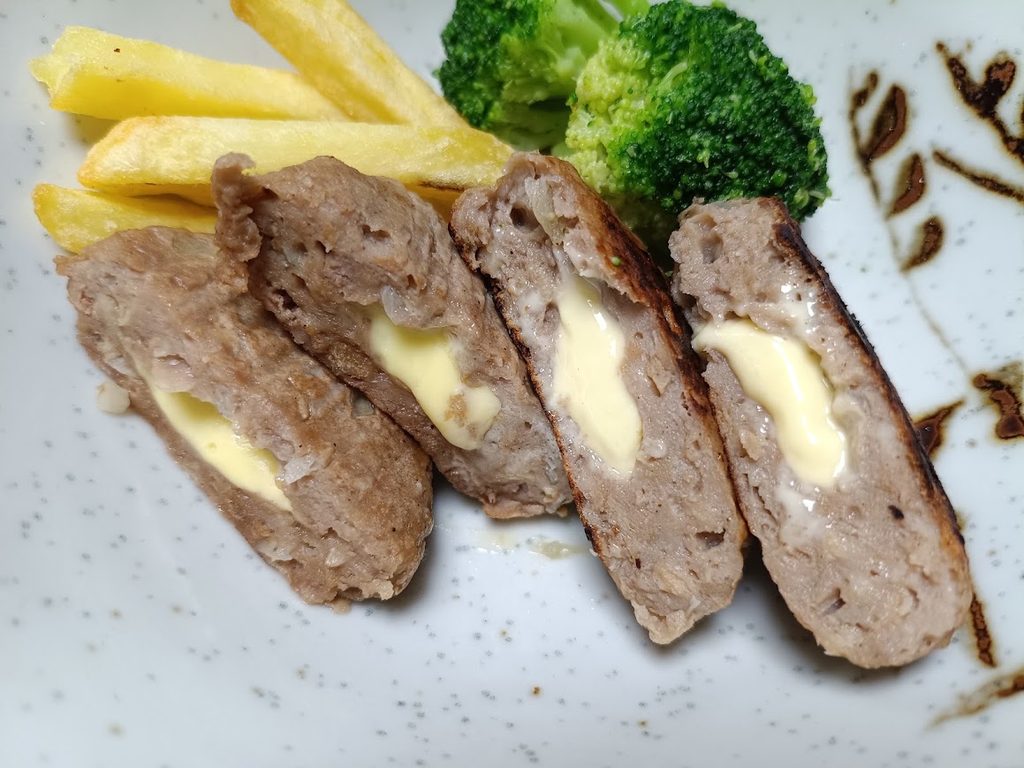 割ったハンバーグを盛った皿。ポテトとブロッコリーが添えられている
