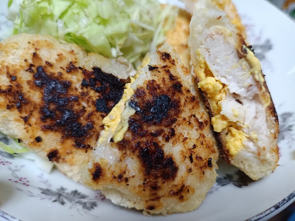 焼いて切ったチキンカツの断面と、せん切りキャベツ