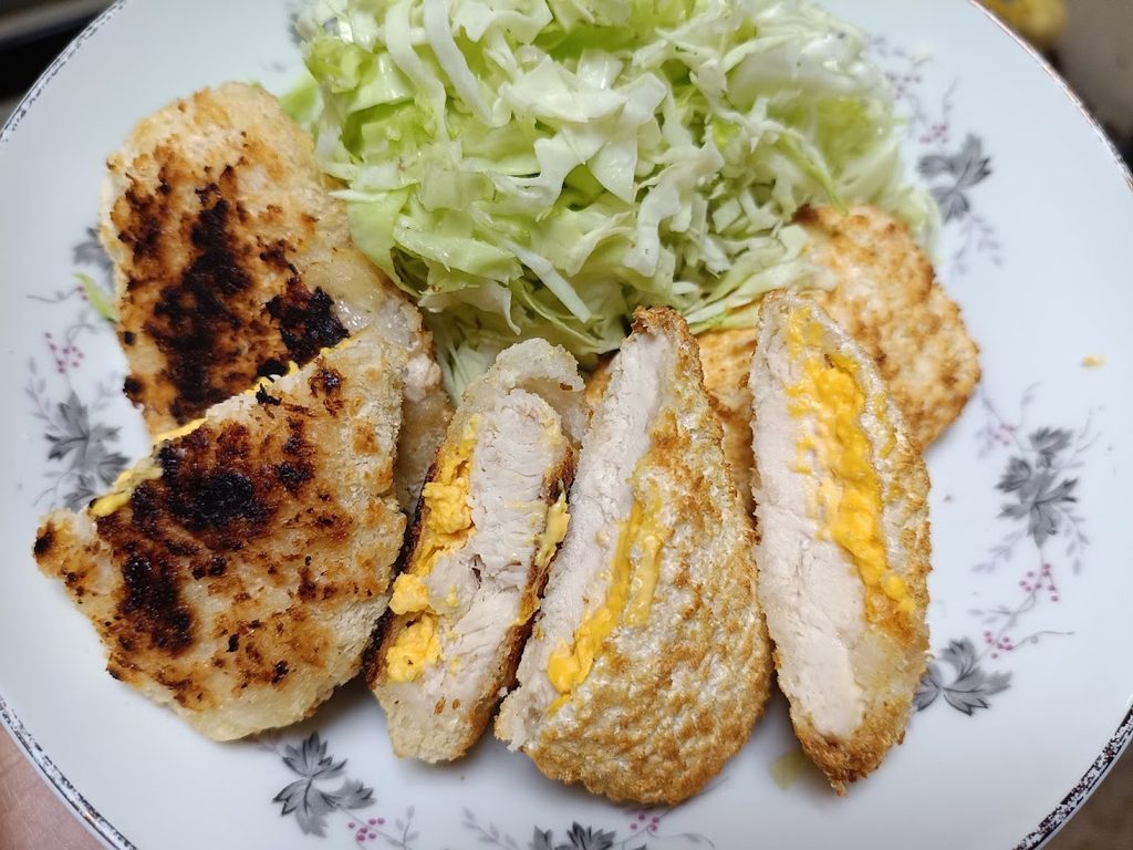 フライパンとノンフライヤーで焼いたチキンカツを並べた皿と、せん切りキャベツ